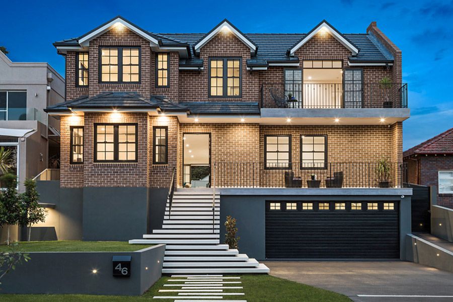 Two-storey brick home with garage and front stairs, lit at dusk